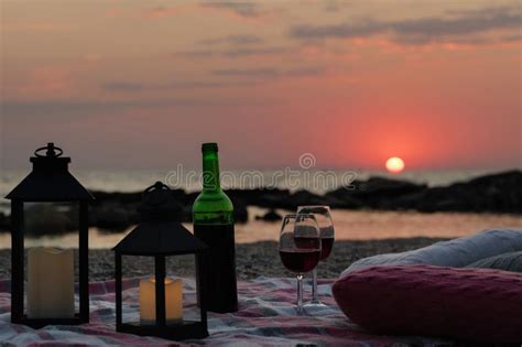 summer sea sunset romantic picnic on the beach bottle of wine glasses candles plaid and