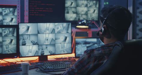 medium shot of a hacker watching hacked security camera footage stock