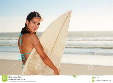 happy female holding a surf board at the sea shore stock