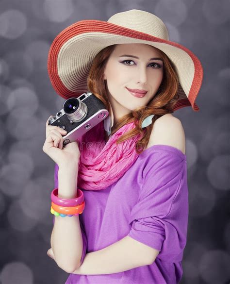 funny redhead girl in hat with camera and bokeh at background stock