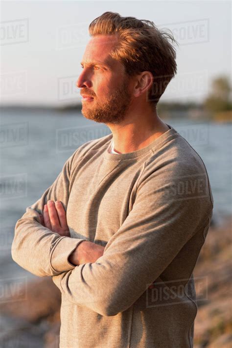 thoughtful man standing arms crossed  beach stock photo dissolve