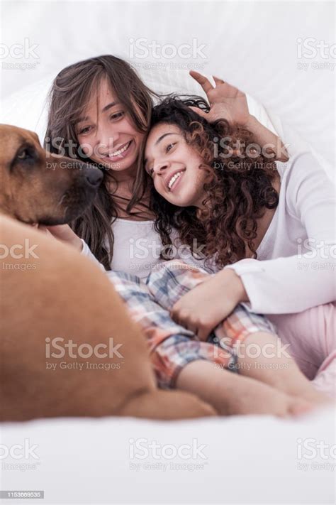 Couple Of Latin Lesbians Are Under The Blanket Smiling As They Watch
