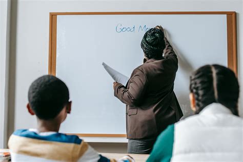 black teacher writing  whiteboard  diverse pupils  stock photo