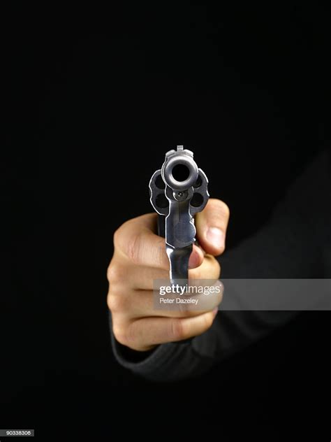 gun pointing at camera on black background foto de stock