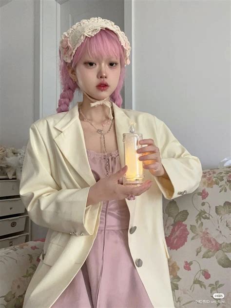 a woman in a pink dress holding a lit candle and wearing a white blazer