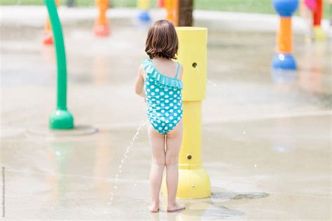 girl playing  water   colorful splash pad  stocksy