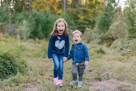 cute brother and sister holding hands and laughing by jakob lagerstedt