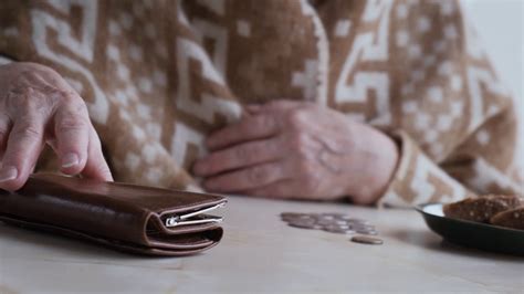 Poor Old Woman Counting Coins While Sitting At Home At The Table
