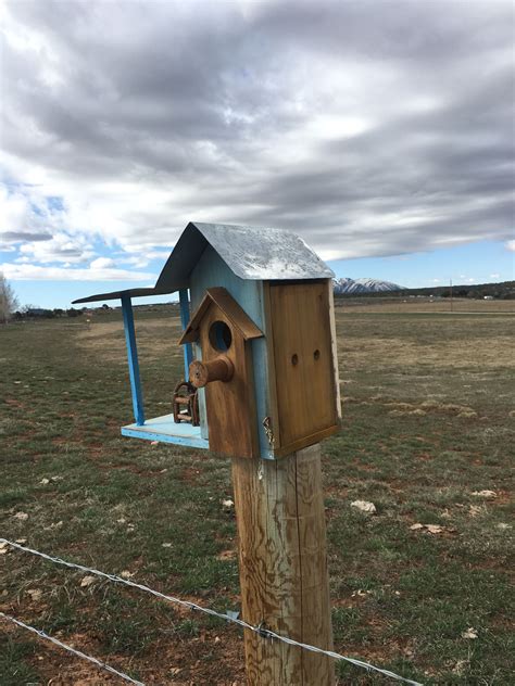 blue birdhouse  top   wooden post   middle   field
