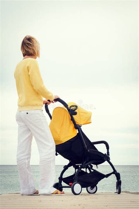 moeder die door het overzees kijken terwijl het lopen met wandelwagen stock foto afbeelding