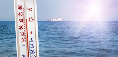 de thermometer op de achtergrond van het overzees  zonnig weer toont  graden van hitte de