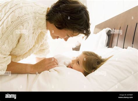 Close Up Of A Mother Bending Over Her Daughter Lying On The Bed Stock