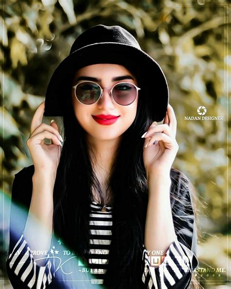 A Woman With Long Black Hair Wearing Sunglasses And A Hat Is Posing For