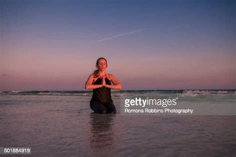 mature woman practicing kneeling yoga pose  beach  sunset high res