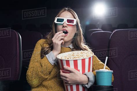 excited woman in 3d glasses eating popcorn and watching