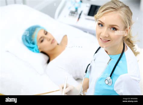 Female Doctor And Young Woman Patient In Hospital Physicians Examine