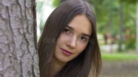 Woman Looks Behind Tree Beautiful Brunette Calm Serious Look Smiles