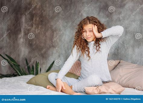 Curly Haired Beautiful Tween Girl In Pajamas Just Waking Up And Sitting