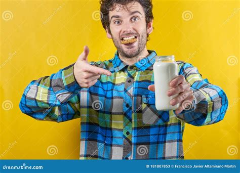 man met een koekje  zijn mond een glas melk  zijn hand en een gelukkig gebaar stock