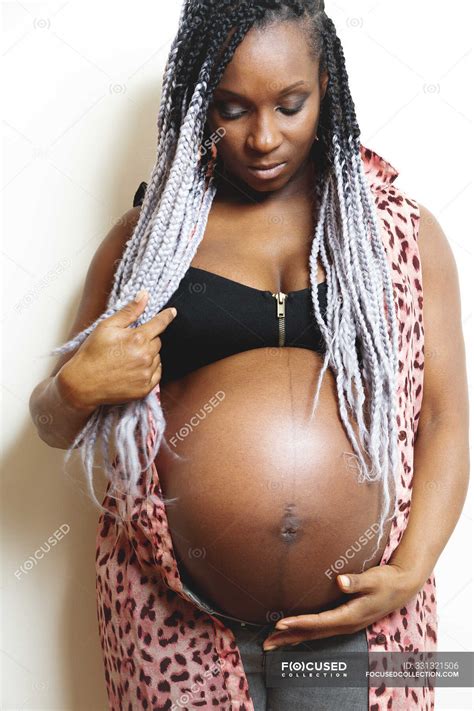 happy african american pregnant woman holding hands on belly — unborn