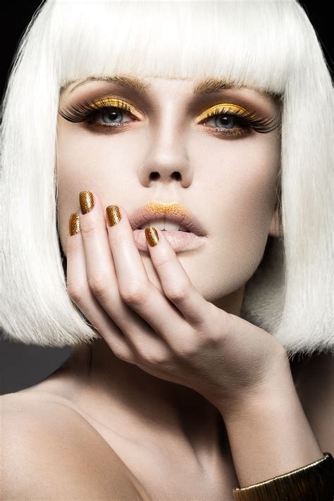 beautiful girl in a white wig with gold makeup and nails