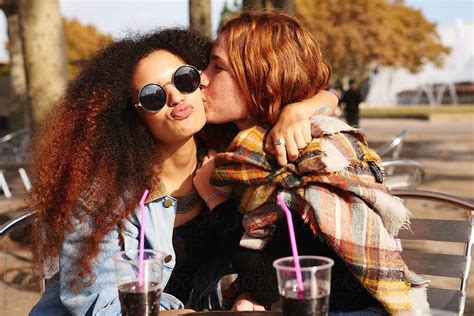 girls kissing in street cafe by stocksy contributor guille faingold