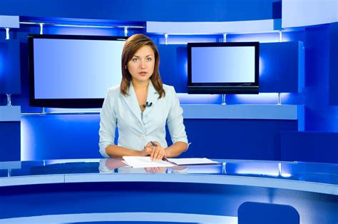 news anchor sitting   desk  front   televisions  monitors