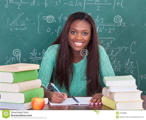 confident female teacher writing  book  classroom desk stock image