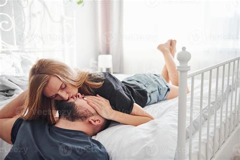 Young Married Couple Kissing Each Other In Bedroom At Daytime 15252633