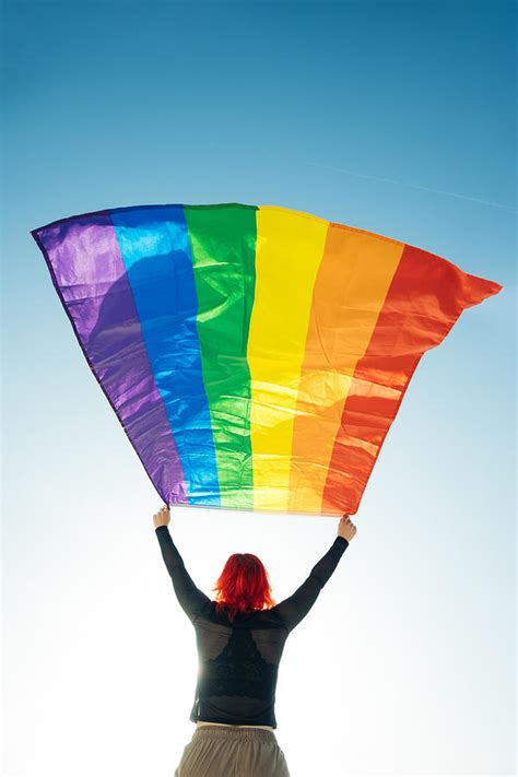 Woman Holding The Gay Rainbow Flag On Blue Sky Background Happiness