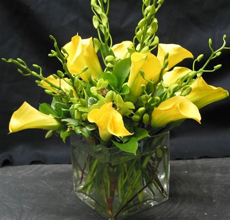 This Is A Cube Vase Floral Arrangement That Features Yellow Miniature