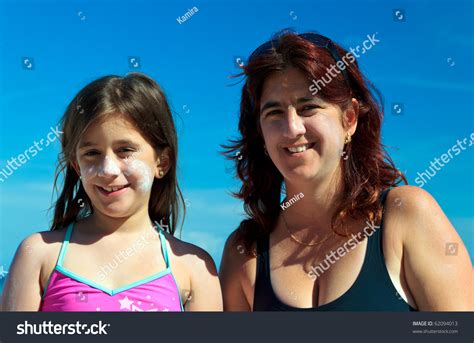 mother and daughter in bathing suits wearing sunscreen
