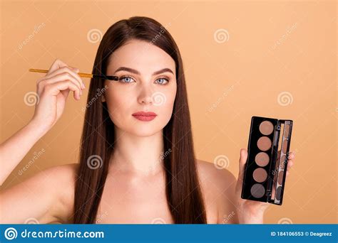 close up photo of focused girl look in mirror apply palette eye shadows