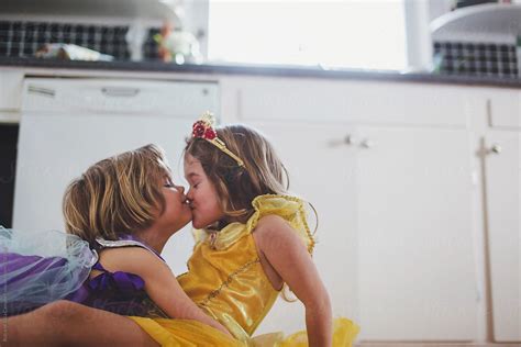 two preschool aged sisters kissing in princess dresses by ameris
