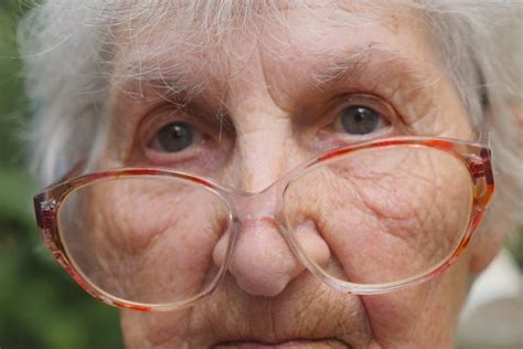 Old Woman In Glasses Looking Into Camera Outdoor Portrait Of Sad