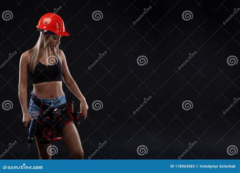 Attractive Girl In Safety Helmet With Tool Belt Holding Electric Drill