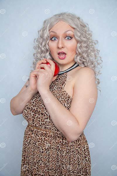 chubby blonde girl wearing summer dress and posing with big red apple