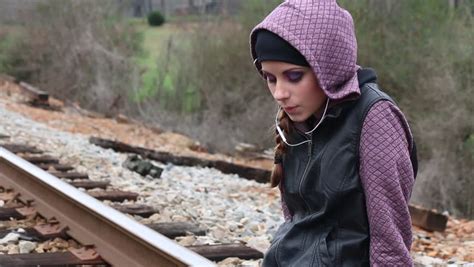 sad teen girl with earphones and hoodie standing on train tracks stock footage video 14627767