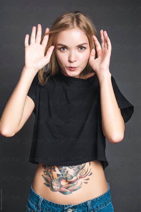Tattooed Young Woman With Naked Stomach And Hands Up By Stocksy