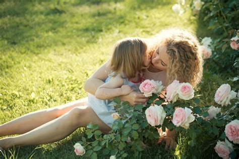premium photo mom kissing daughter on green grass on sunny summer day