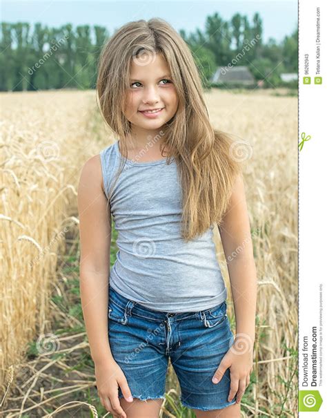 menina sexy com o cabelo longo que levanta no campo de trigo em um dia de verão imagem de