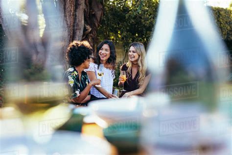 Group Of Women Sitting Outdoors With Wine And Gossiping
