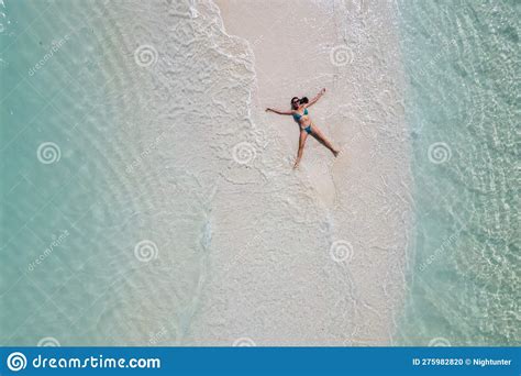 young woman tanning sunbathing woman wearing bikini   beach   white sand   view