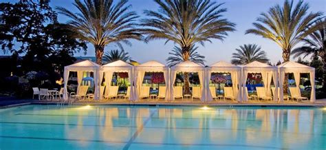 large swimming pool surrounded  palm trees  white tents