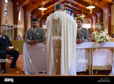 catholic priest administers wedding vows to two latino american couples
