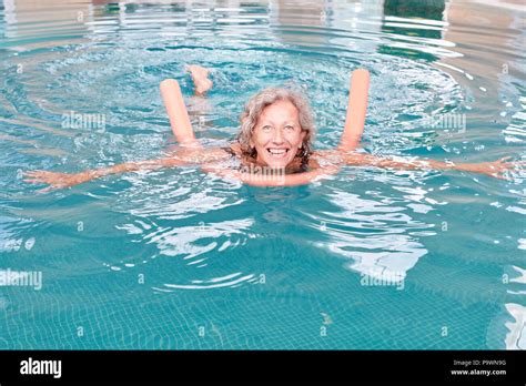 Vital Senior Woman In Pool With Swimming Aid In Rehab Doing Aqua