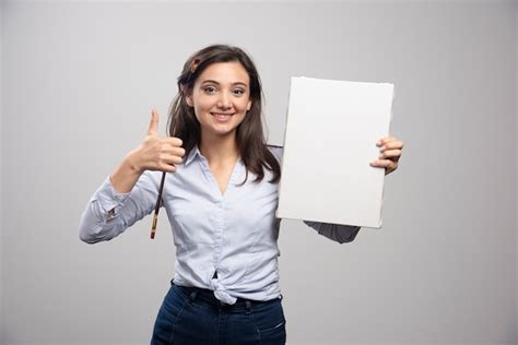 Free Photo Brunette Painter Holding Canvas And Giving Thumbs Up
