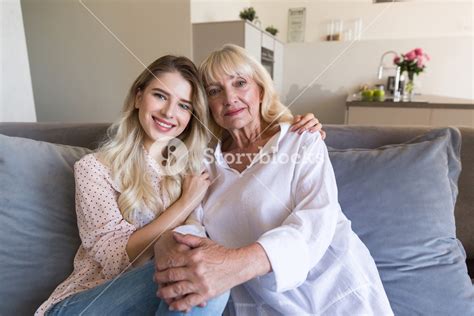Smiling Granddaughter And Grandmother Sitting Together On A Couch And