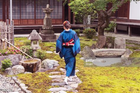 Mature Japanese Woman In Traditional Kimono Walking In Zen Garden At A