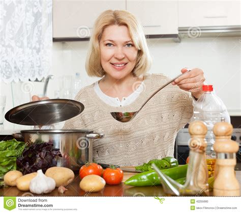 mooie rijpe vrouwen kokende soep stock foto afbeelding